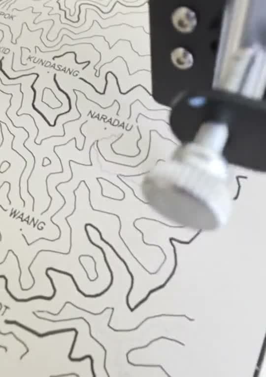 Gros plan : la pointe du stylo et les courbes de niveau sur papier crème
